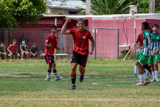 Teen soccer player celebrates on the field during an outdoor match game.