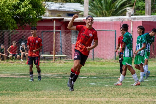 Young soccer players in vibrant jerseys celebrating a goal outdoors.