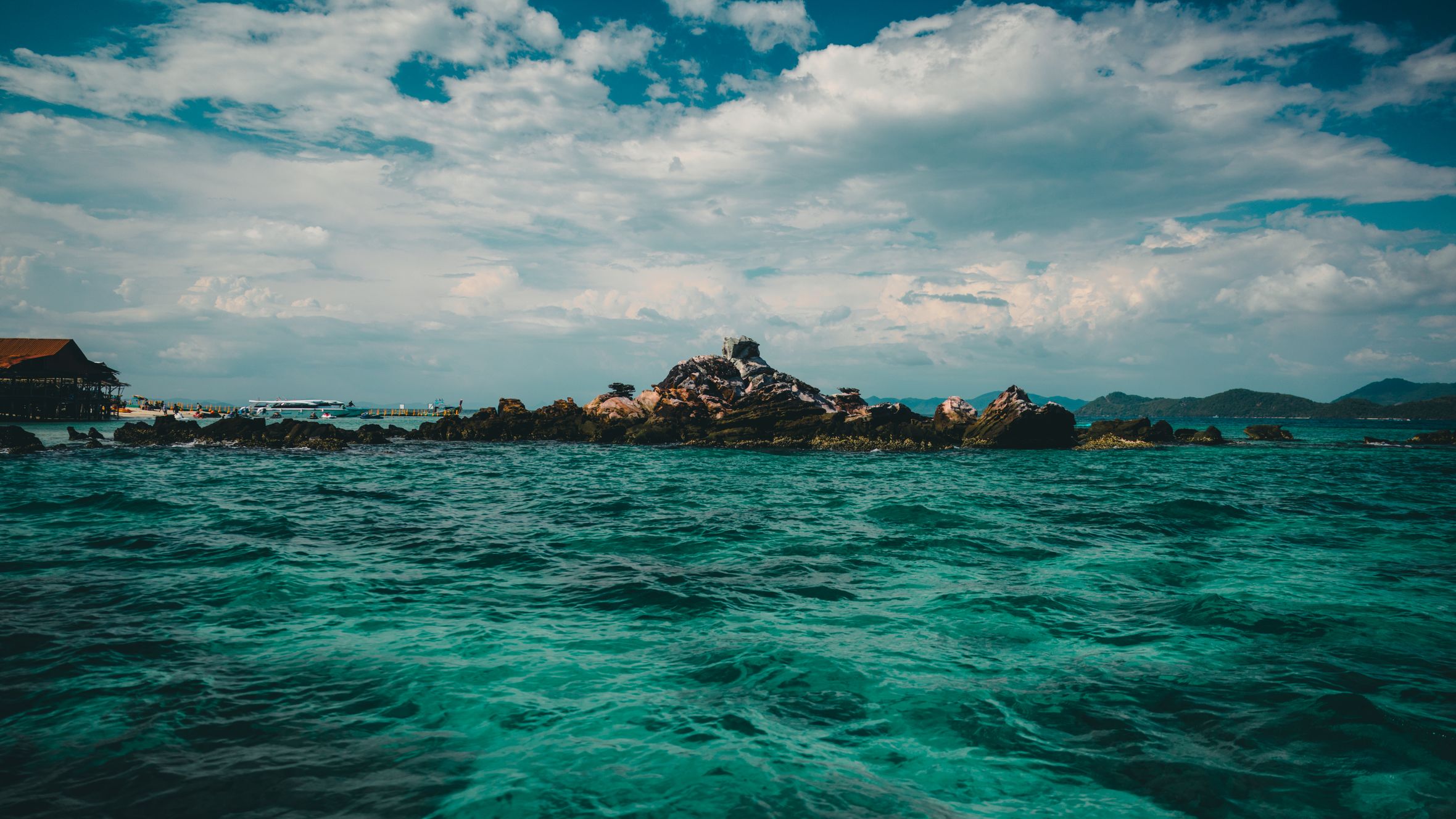 Breathtaking view of a rocky island in the turquoise sea of Phuket, Thailand under a dramatic sky.