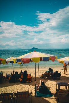 Relaxing scene at Phuket beach with colorful umbrellas and people enjoying the sun and sea.
