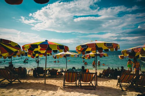 Free Colorful umbrellas and loungers on a lively beach in Phuket, Thailand, during a sunny day. Stock Photo