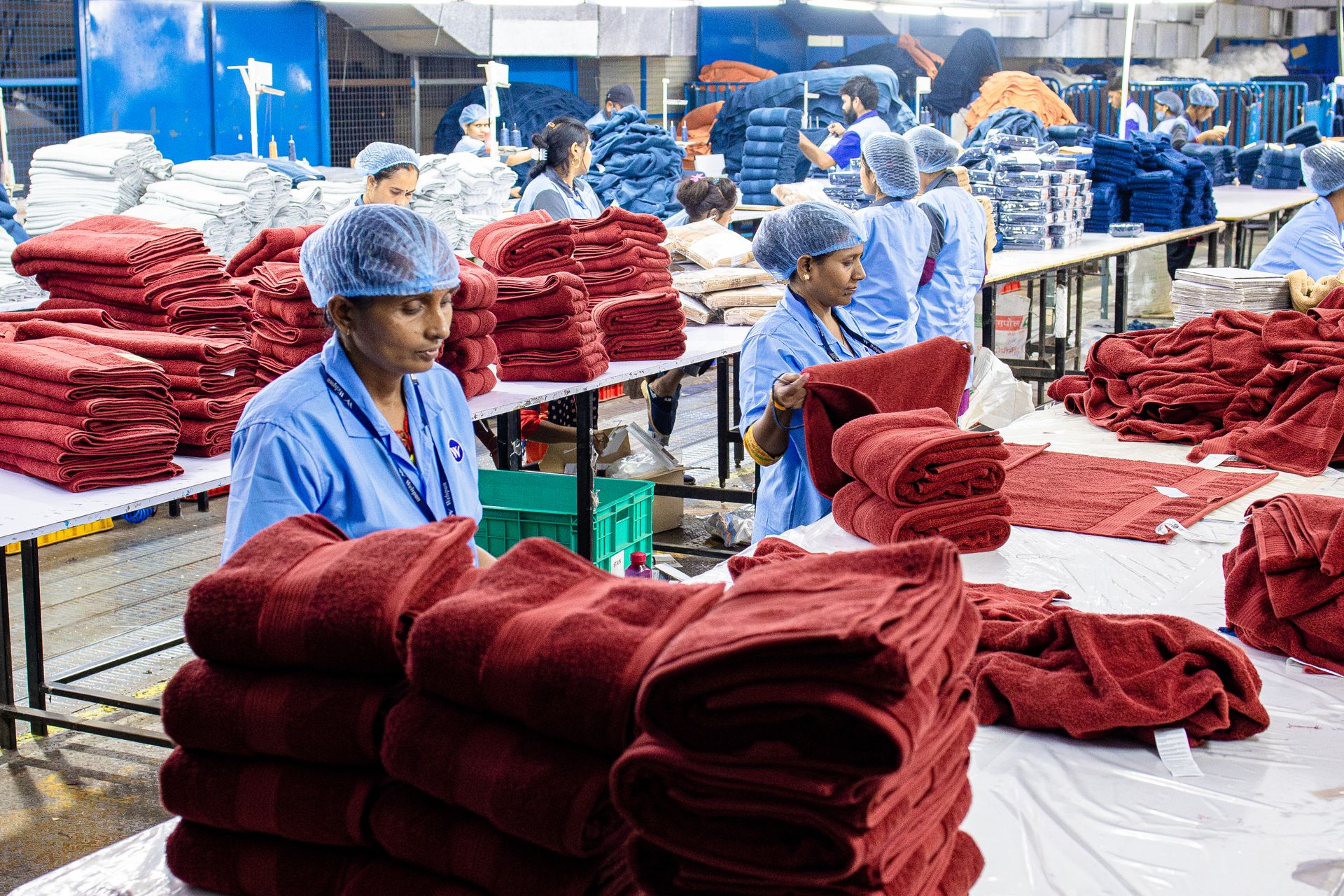 Workers in an Indian factory fold towels efficiently. Textile industry scene.