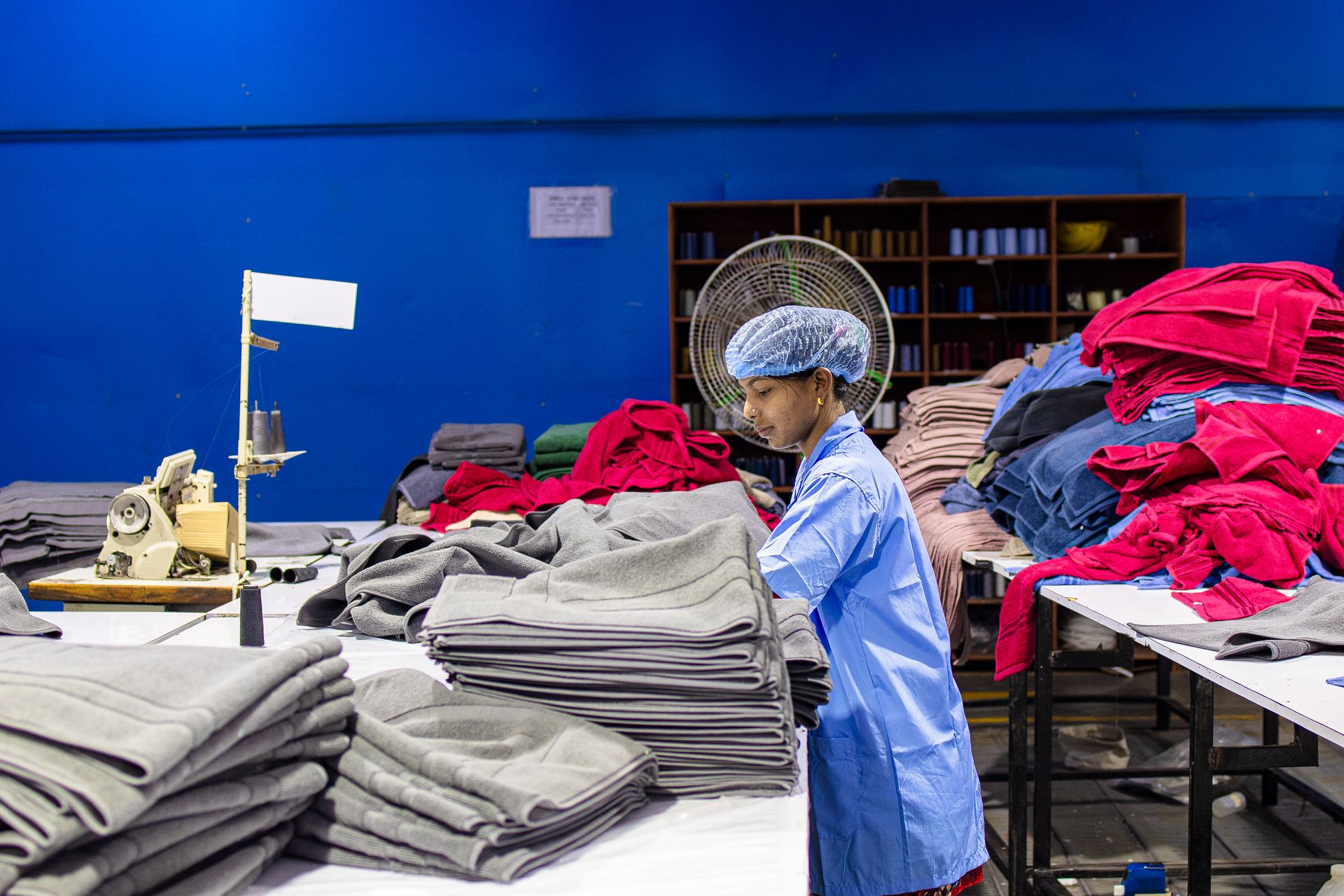 Female worker in a textile factory sorting fabric piles, showcasing industrial labor.
