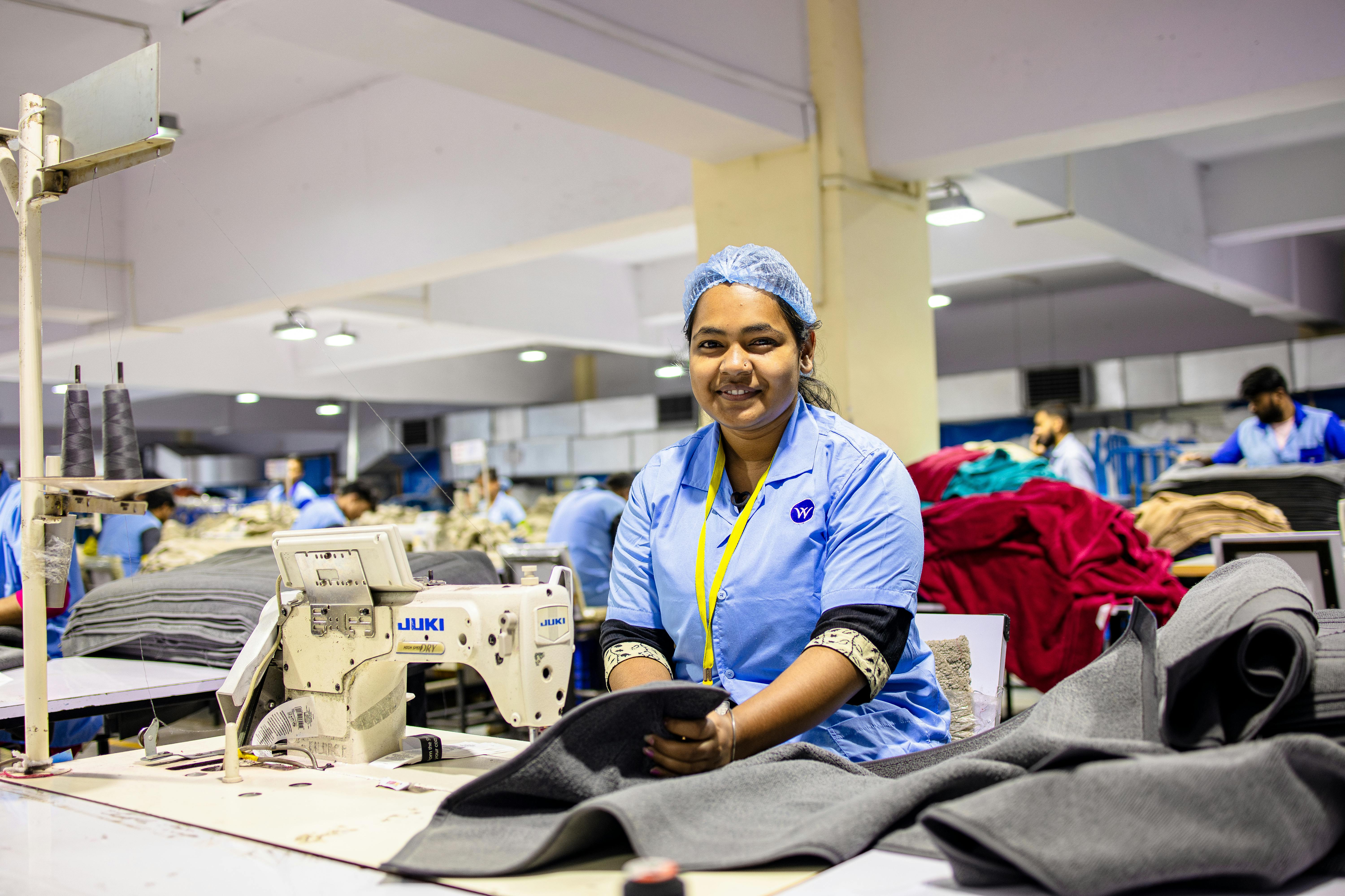 Portrait of a cheerful factory worker sewing garments in a textile facility.