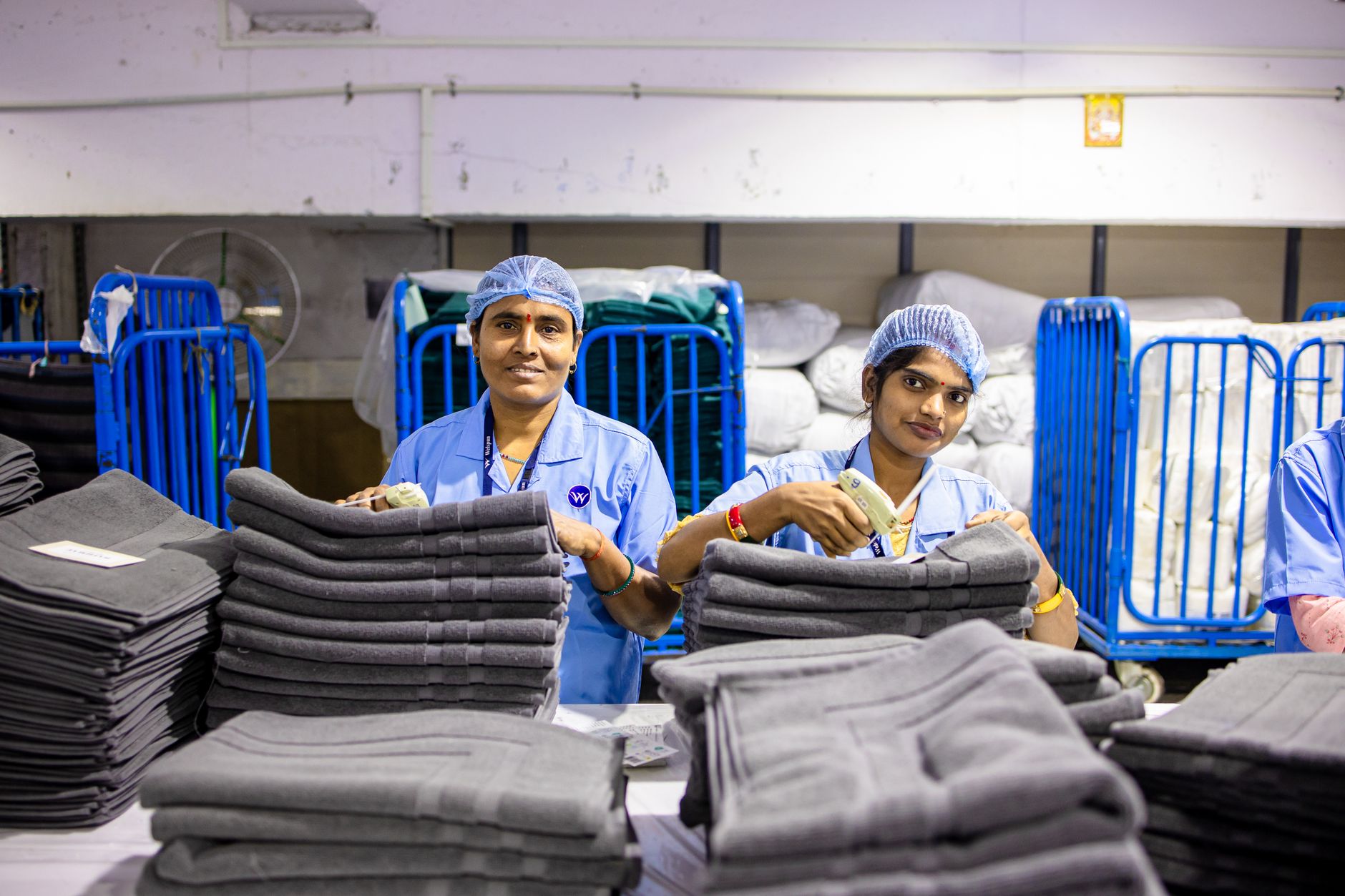 A woman holding a linen garment up to the light, inspecting the weave density and fabric quality.