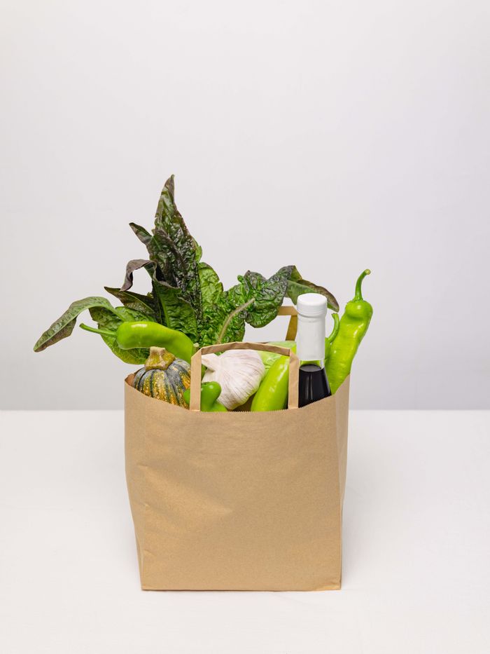 A kraft paper grocery bag filled with fresh greens, peppers and a squash — photo by SU JI on Pexels