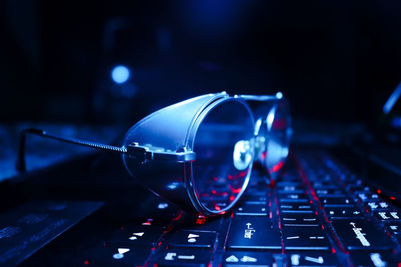 Gafas apoyadas sobre el teclado iluminado de un portátil por la noche