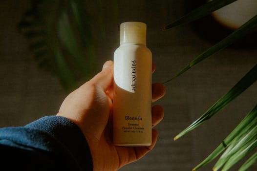 A close-up of a hand holding a Blemish Enzyme Powder Cleanser in natural light.