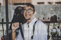 透过玻璃板，一位戴眼镜的年轻人肖像微笑着，散发着时尚与自信