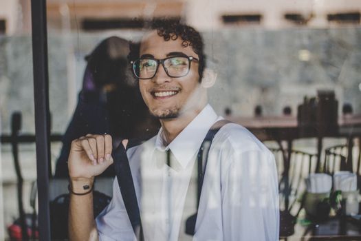 透过玻璃板，一位戴眼镜的年轻人肖像微笑着，散发着时尚与自信