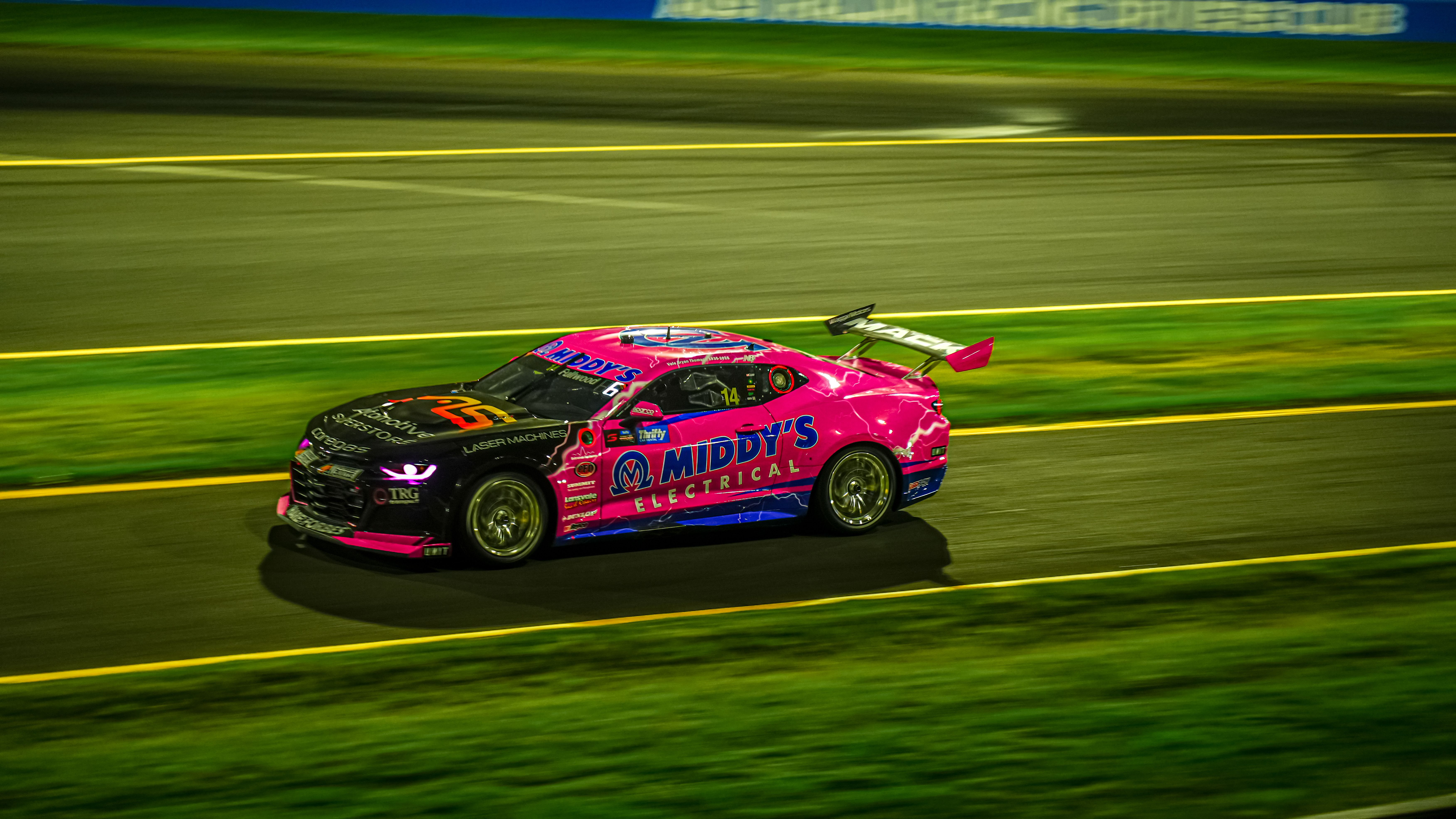 a night racing circuit with bright lights, sleek cars accelerating through a sharp corner
