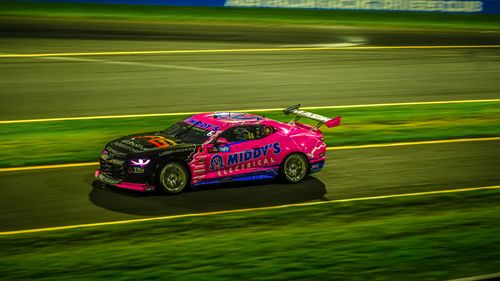 Free Bright pink race car speeding on a track at night, showcasing motion and excitement. Stock Photo