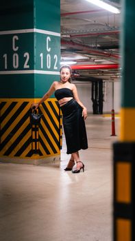 Stylish woman in black dress posing in an İzmir parking garage.