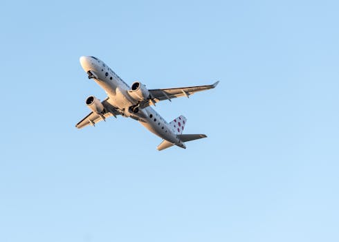 A commercial jet airplane flying high above Prague on a clear day, showcasing aviation travel.