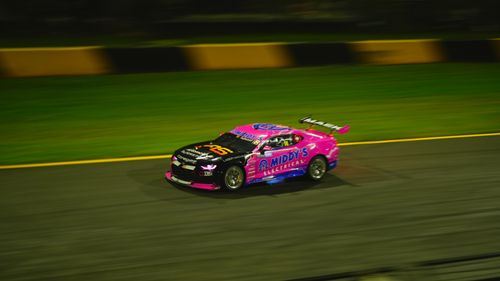 Free Brightly colored race car speeding on a night race track. Stock Photo