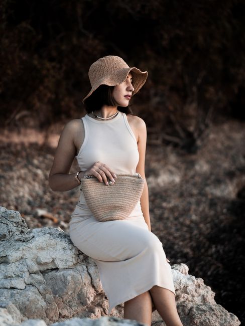 Stylish woman wearing a dress and straw hat by the coast in İzmir, Türkiye.