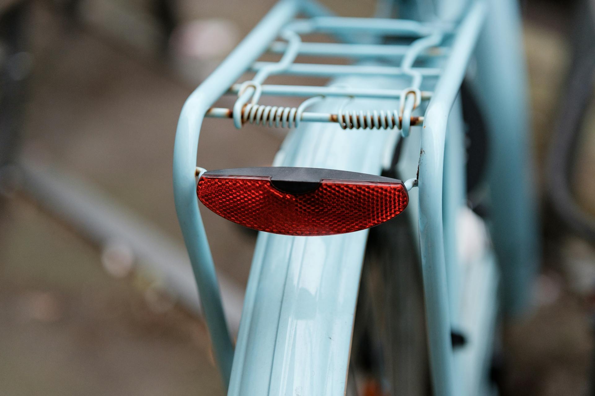 Detailed close-up of a blue bicycle's rear rack and red safety light.