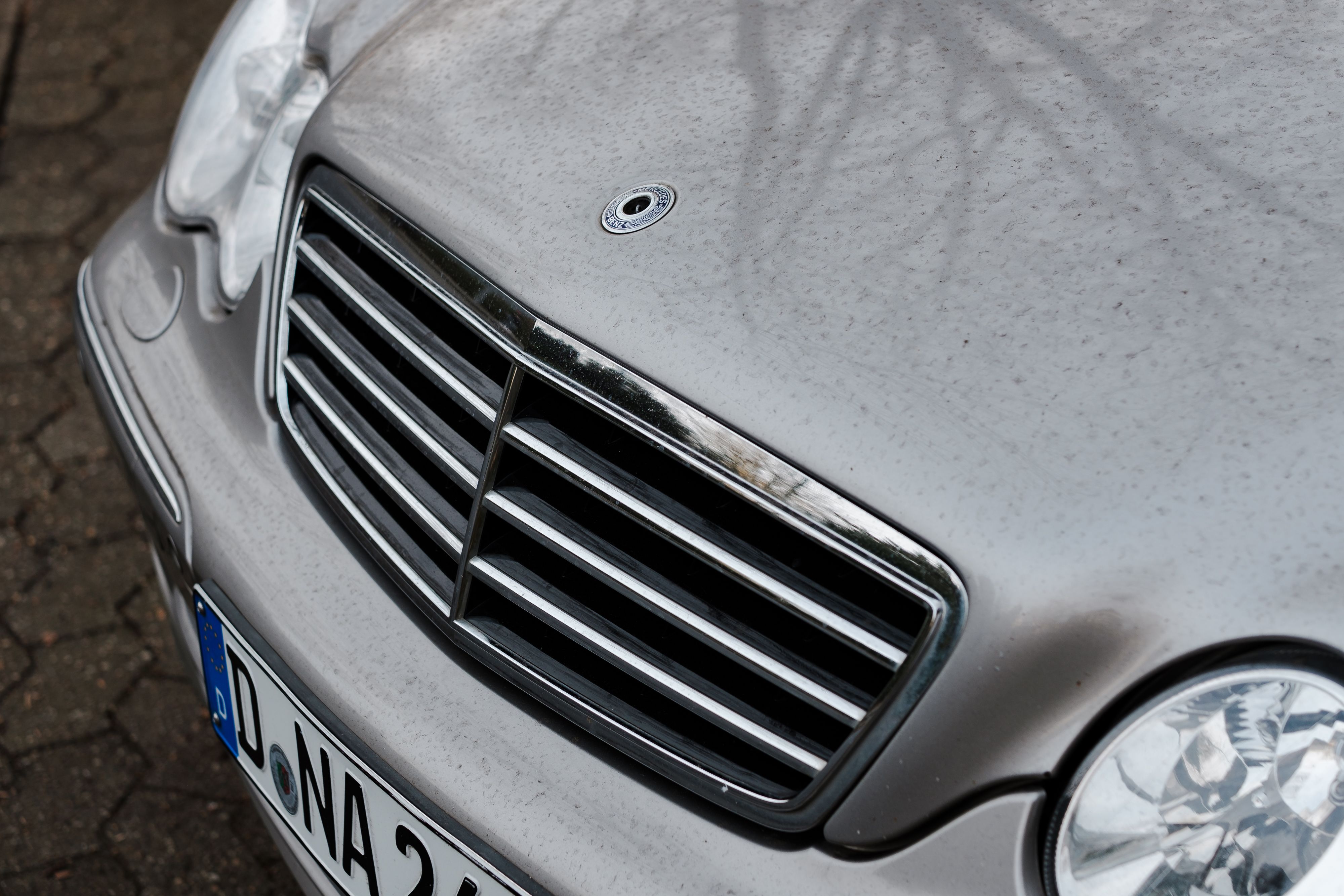Detailed view of a luxury car's front grille with chrome accents and a European license plate.