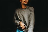一位身穿休闲装的男子肖像，背景为黑色，灯光阴郁