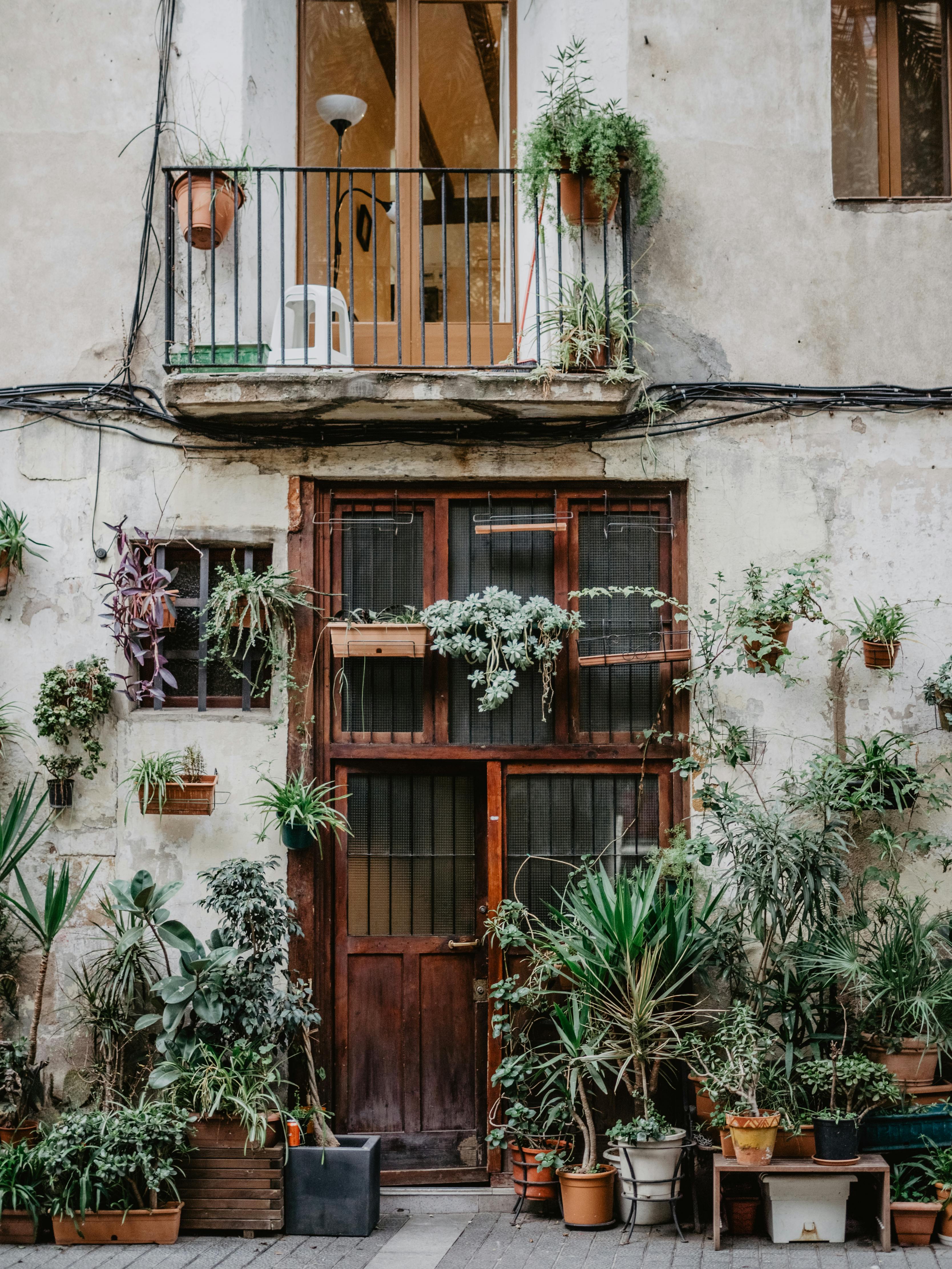 Rustic facade in Barcelona featuring a charming balcony adorned with vibrant plants.