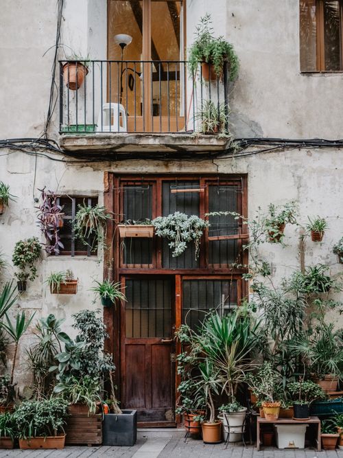 Free Rustic facade in Barcelona featuring a charming balcony adorned with vibrant plants. Stock Photo