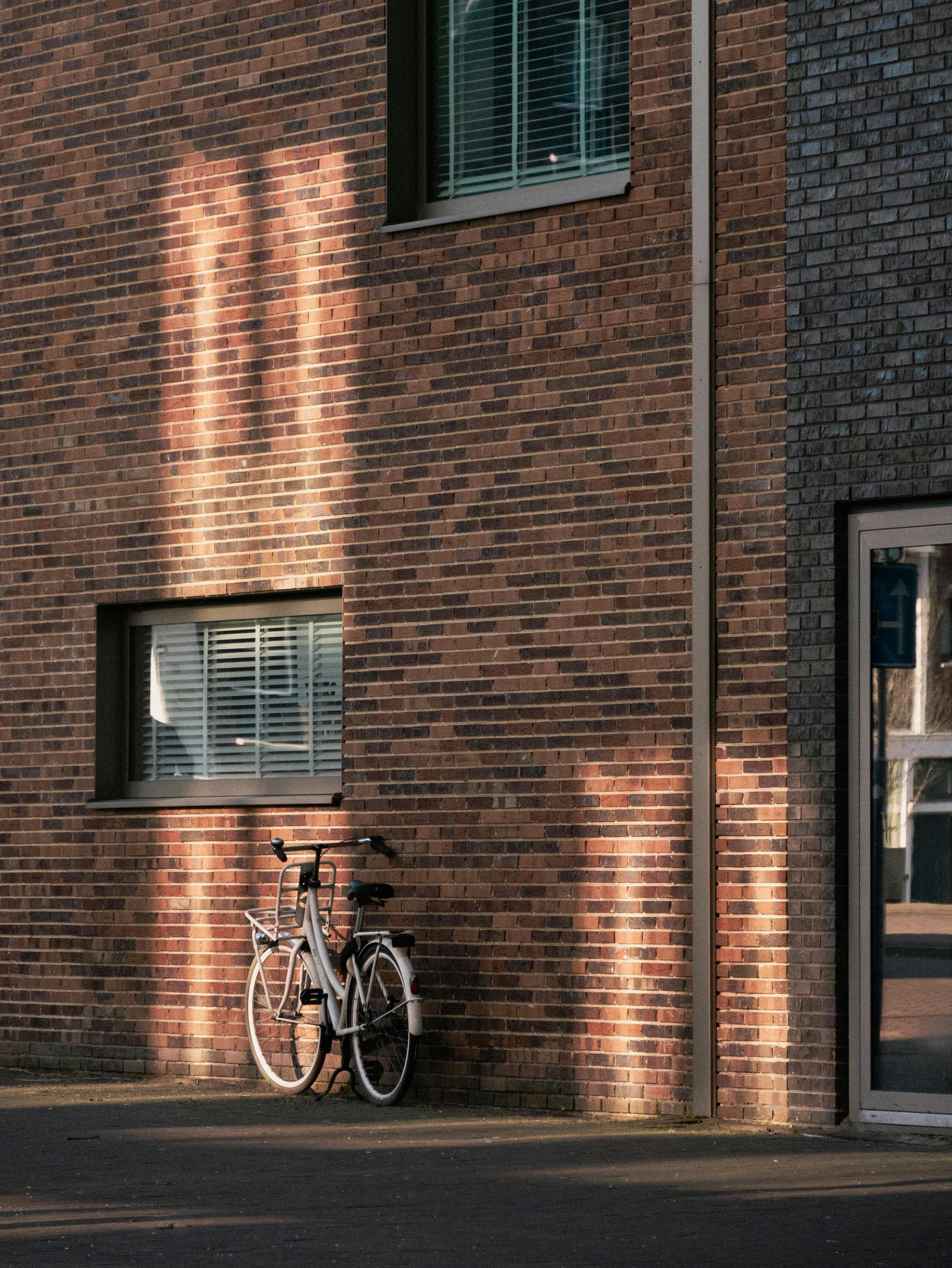 A classic bicycle rests against a sunlit brick wall in Amsterdam.