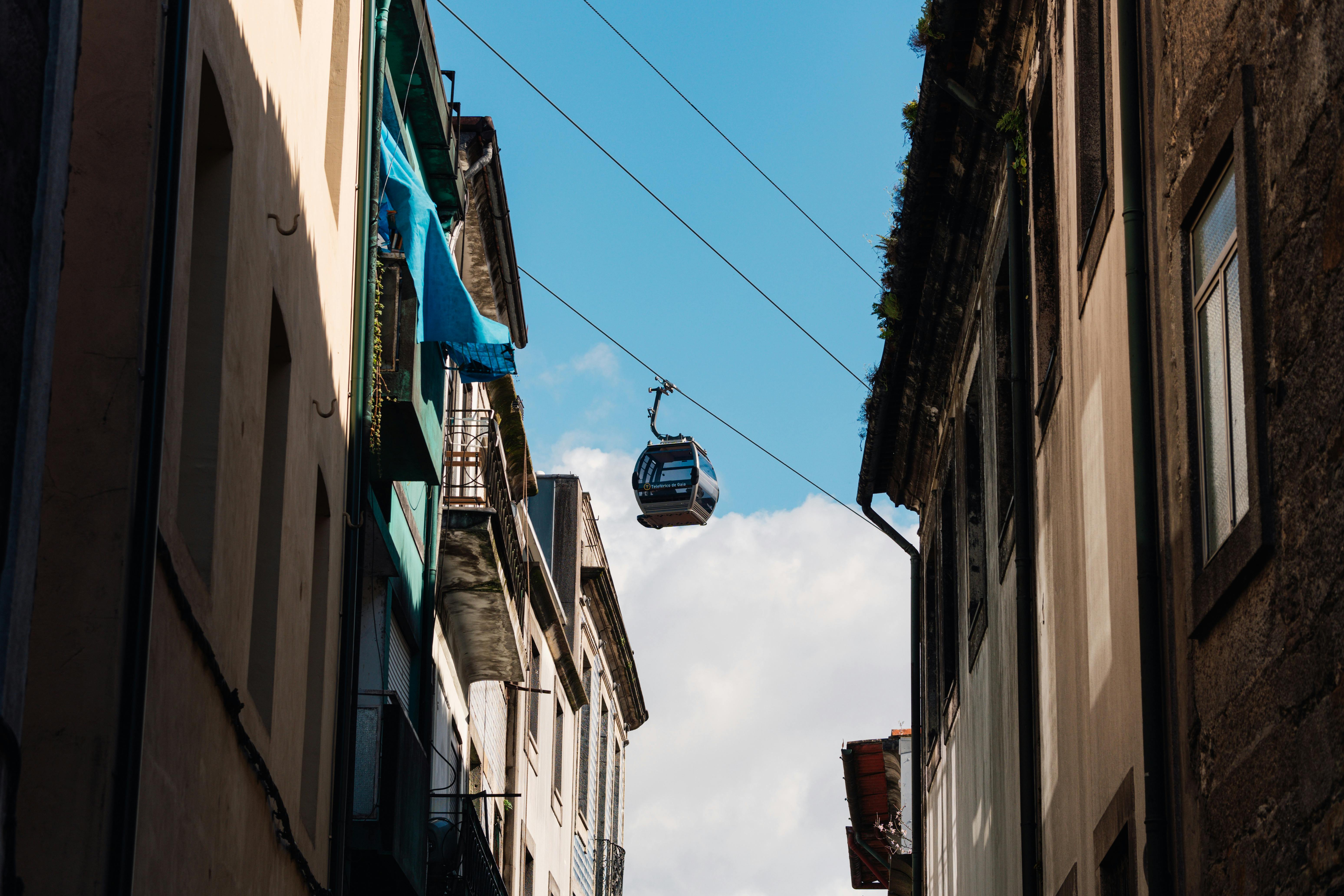 A cable car traverses the sky between traditional buildings in Porto, Portugal.