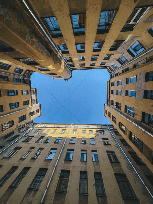 Free Looking up in a historic building courtyard with clear blue sky. Stock Photo