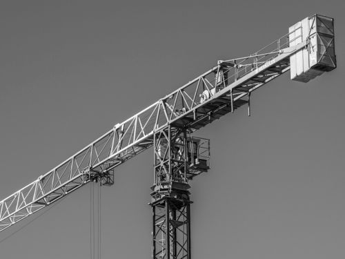 Free A monochrome image of a construction crane against a clear sky, showcasing industrial design. Stock Photo