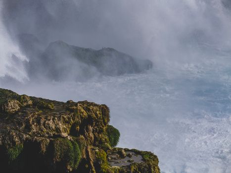 Stunning view of a powerful waterfall cascading over moss-covered rocks.