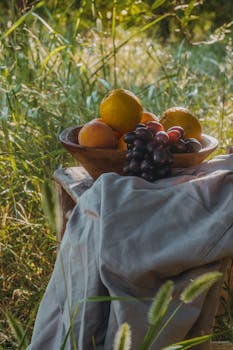 A wooden bowl of assorted fruits in a sunlit garden, conveying warmth and freshness.