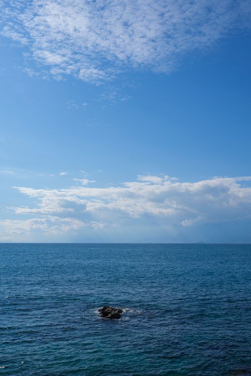 Free Peaceful ocean view with a rocky foreground and a vast open sky. Stock Photo