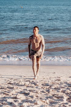 A man covered in sand walks along Porto Seguro beach during a sunny summer day.