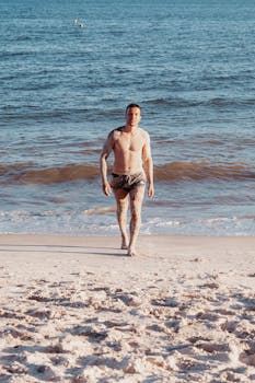 A man strolls on Porto Seguro's beach under a clear blue sky.