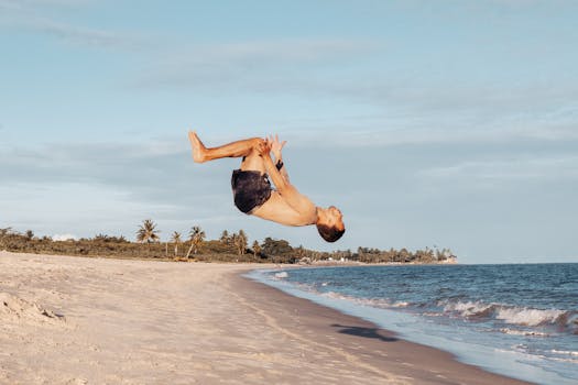 Athletic man doing a backflip on a beach in Porto Seguro, Brazil.
