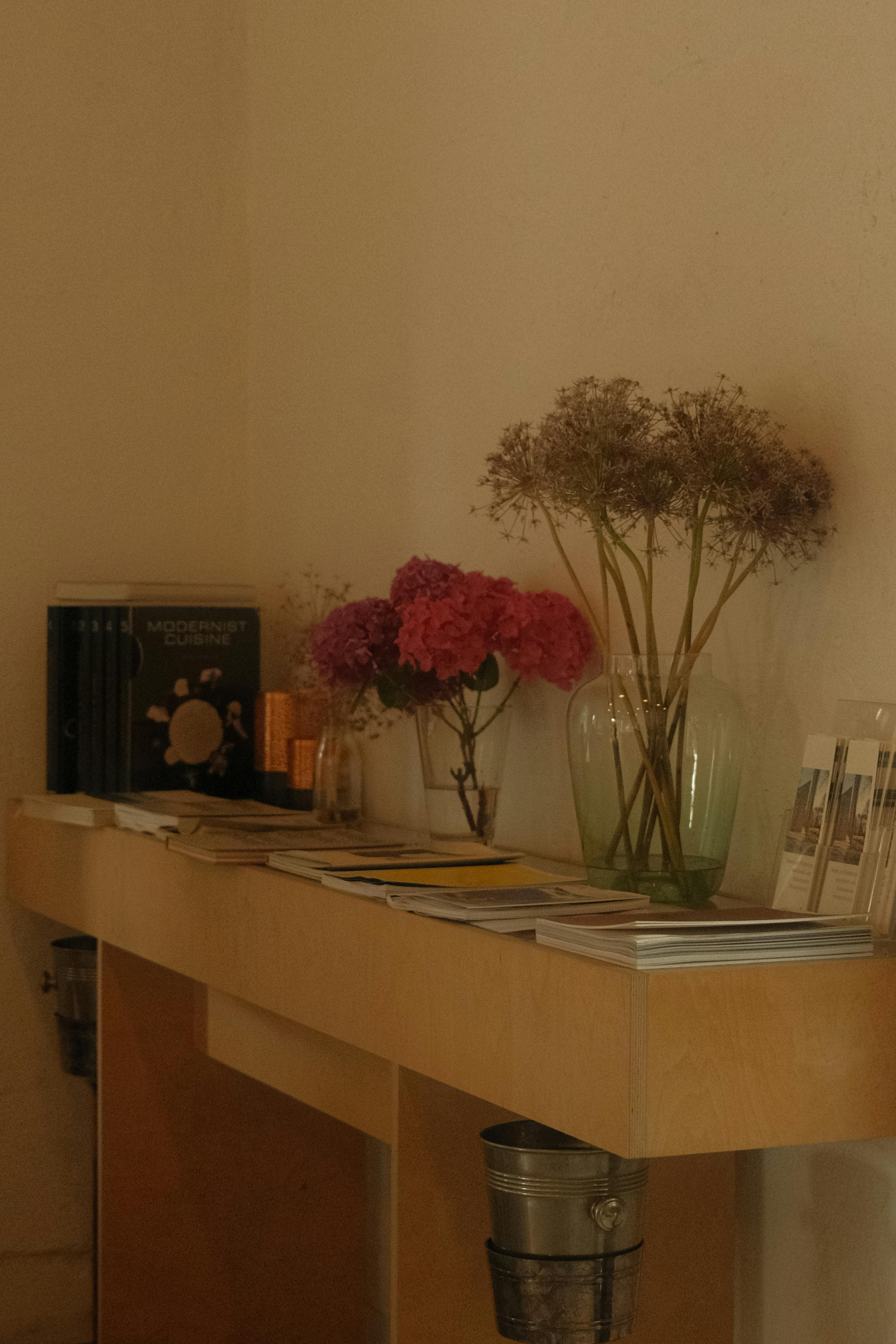 Kostenlos Ein hölzerner Konsolentisch mit Blumen, Büchern und Dekor, aufgenommen im Innenbereich. Stock-Foto