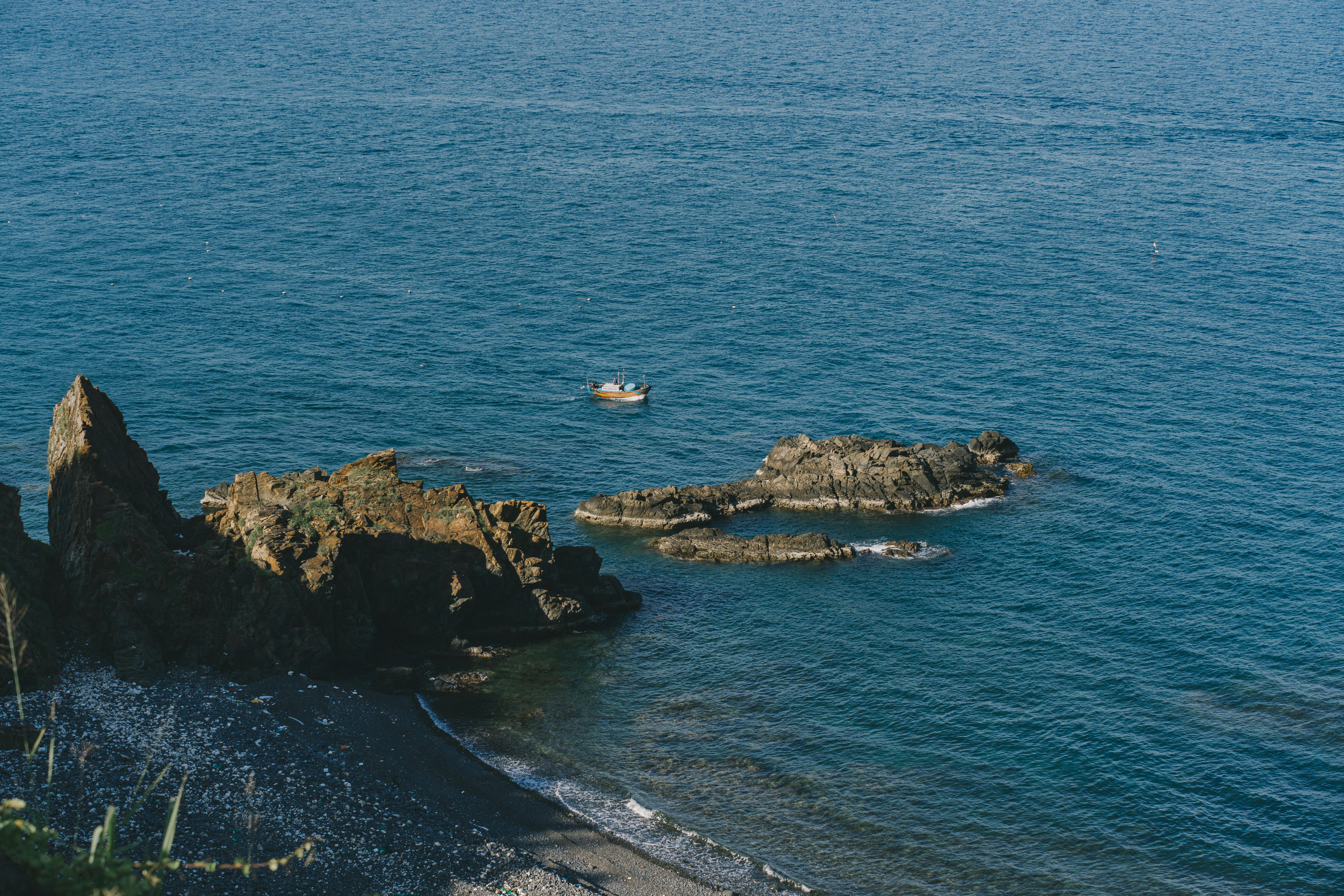 A tranquil coastal scene featuring rugged rocks and calm blue waters.