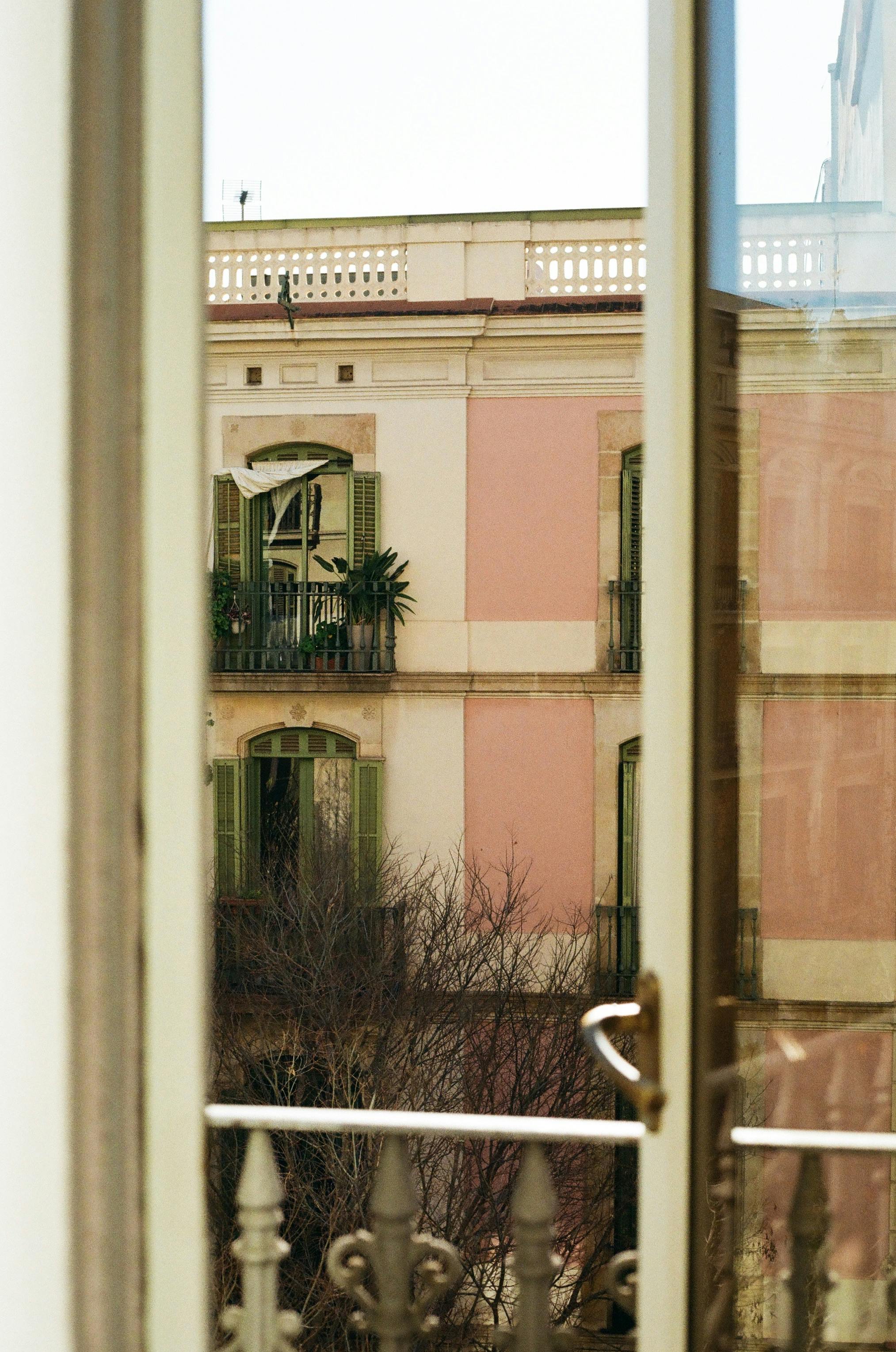Scenic view of a charming balcony and facade in Barcelona, captured through a window.