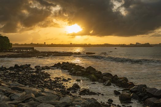 Dramatic sunset view over the rocky shoreline of Galle, Sri Lanka, with vibrant sky and ocean waves.