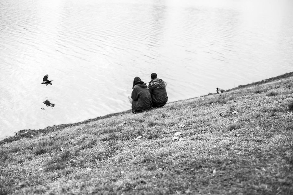 Couple sitting by a lake in Zagreb, enjoying a peaceful moment in black and white.