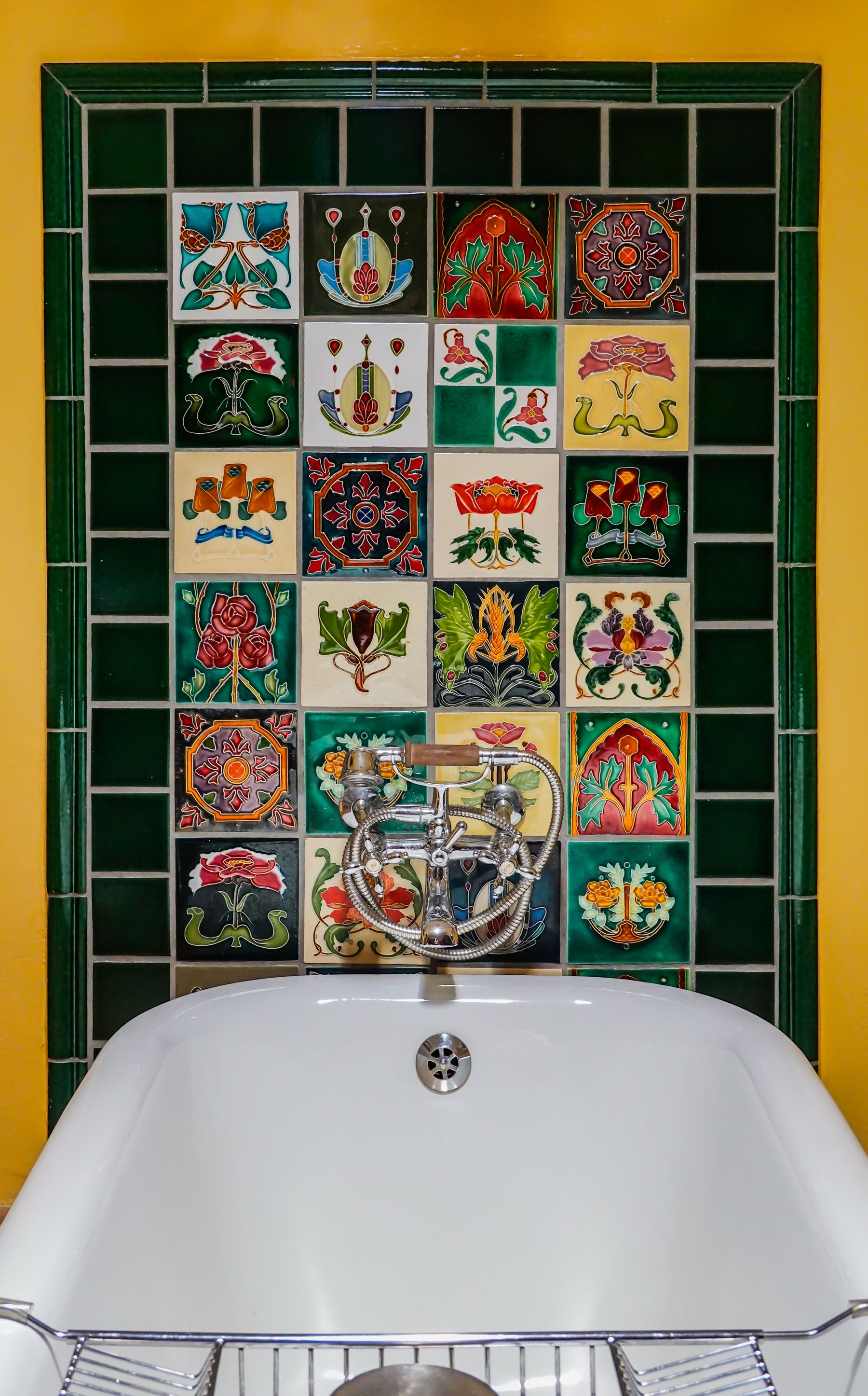 Art Deco-inspired bathroom with colorful geometric tile, vintage detailing and a freestanding bath