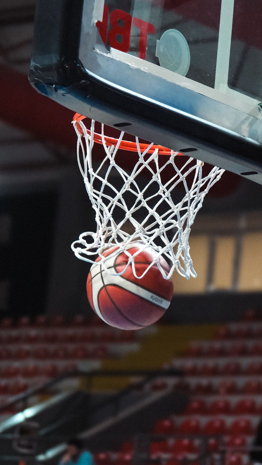 Basketball going through the hoop captured mid-action in an indoor stadium