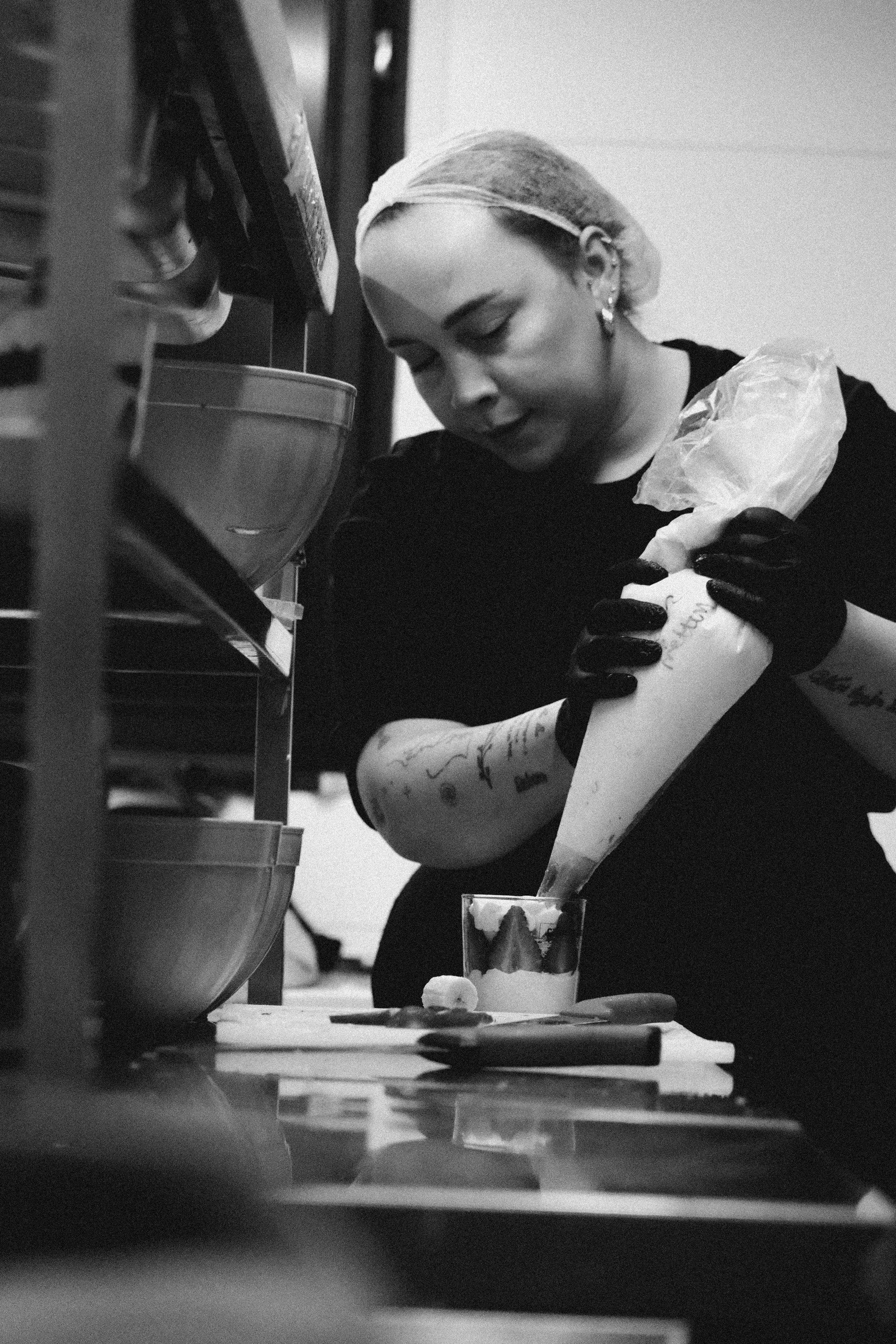Black and white image of a pastry chef skillfully decorating a dessert.