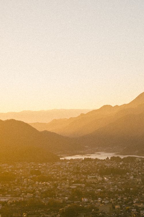 Free A serene mountain view at sunset with warm tones over a town. Stock Photo