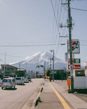 Scenic street view with the iconic Mount Fuji towering in the background under clear skies.