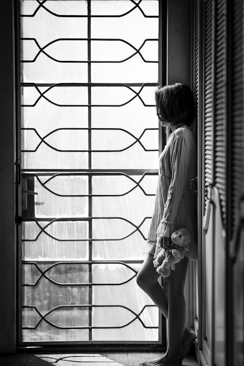 Фотография женщины, стоящей у закрытой стеклянной двери