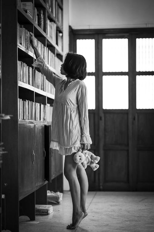 Monochrome Photo Of Woman Reaching For Book