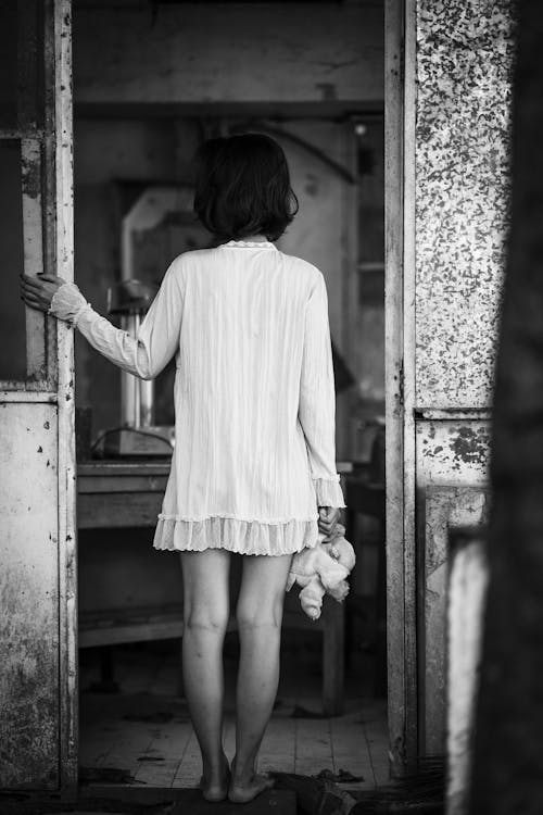 Монохромное фото женщины, стоящей на дверном проеме