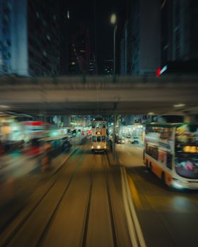 Dynamic view of Hong Kong's bustling streets featuring trams and neon lights at night.
