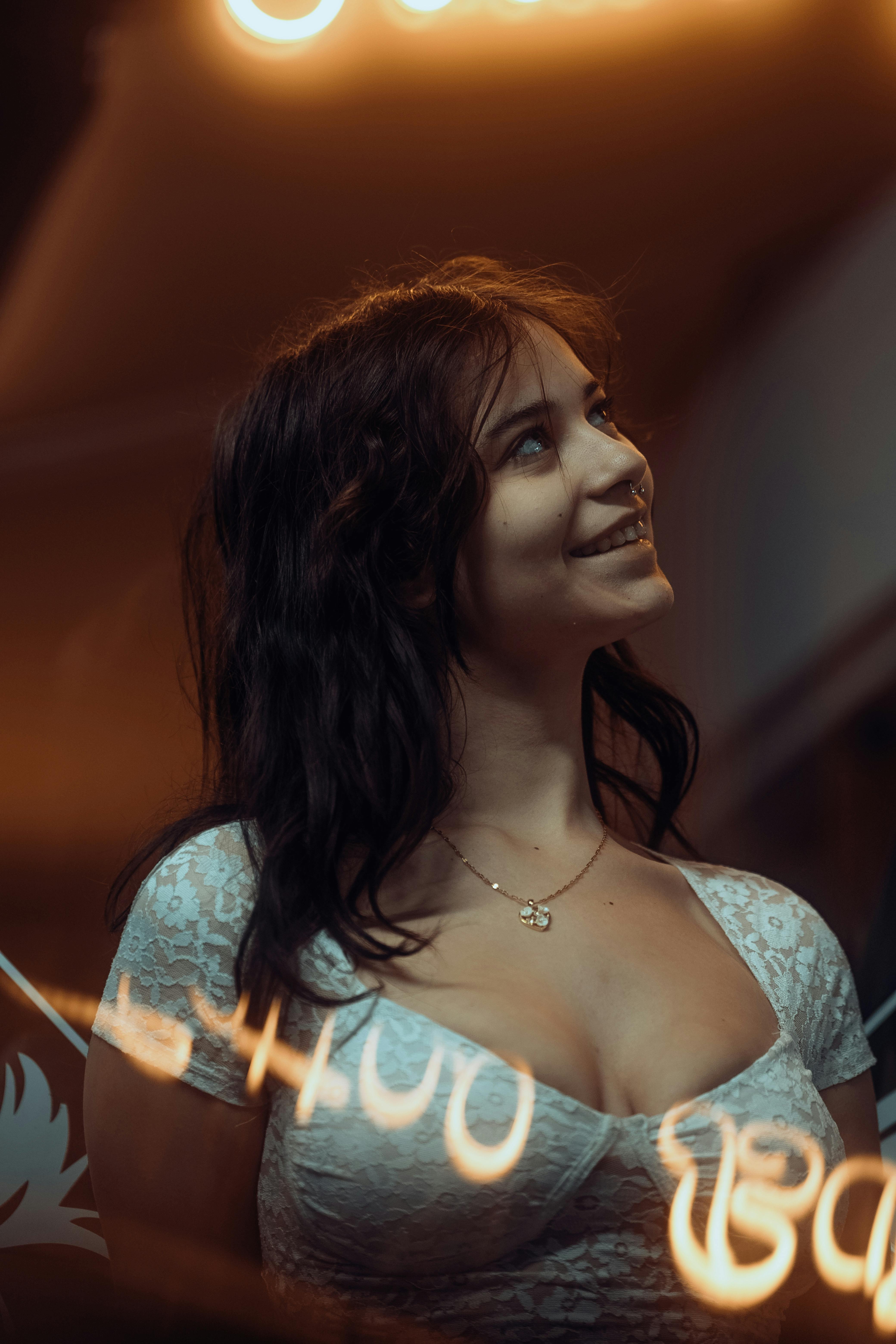 Young woman looking upward amid neon lights, evoking a moody and artistic atmosphere.